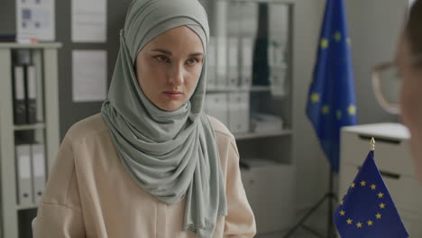 muslim woman filling out immigration form with help from visa officer