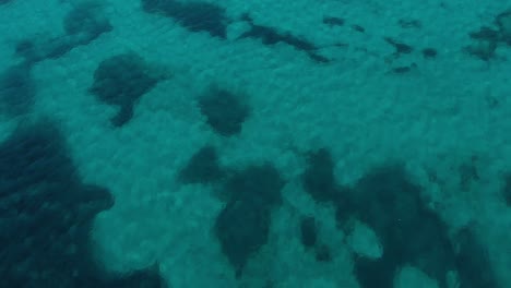 aerial, tilt up, drone shot over shallow, turquoise ocean, revealing the coast of mallorca, on a sunny day, in balearic islands, spain