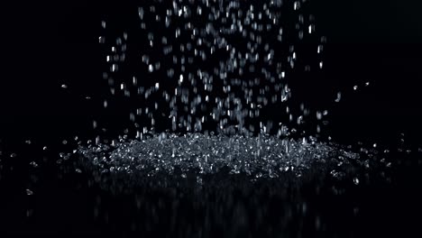 diamantes cayendo sobre una superficie negra reflejada contra el negro