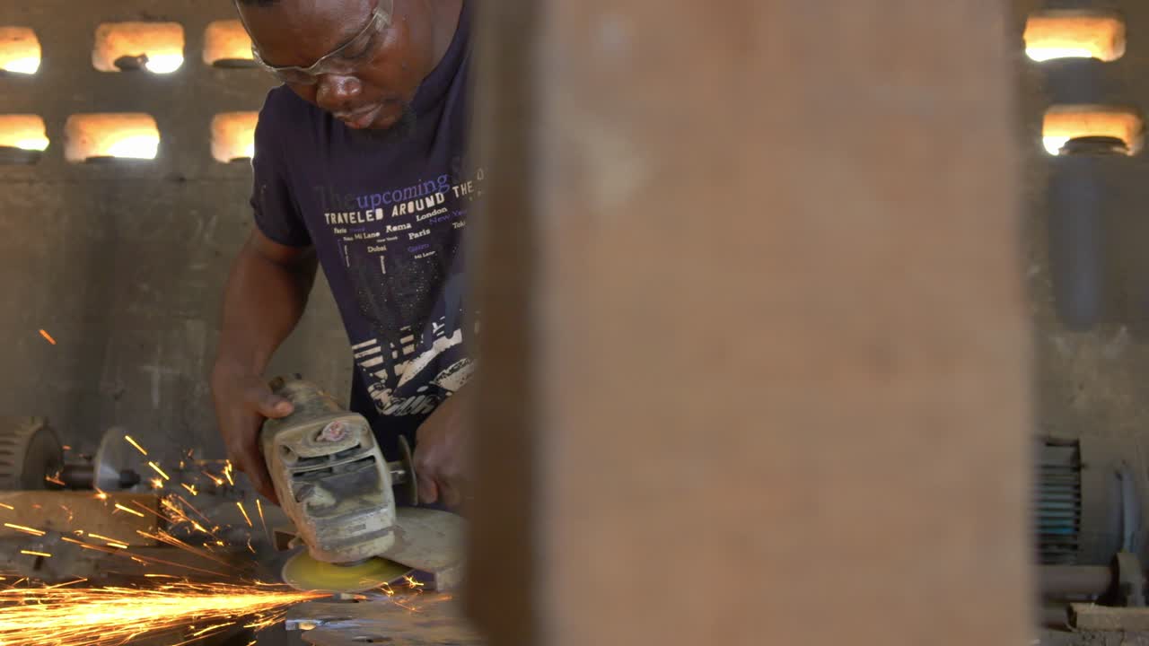 African American Steel Male Worker Polishes a Metallic Saw at Workshop Body Shot