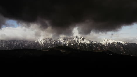 nubes oscuras en la cima de las montañas rocosas cubiertas de nieve en predeal mountain resort rumania, paisaje salvaje de las montañas bucegi