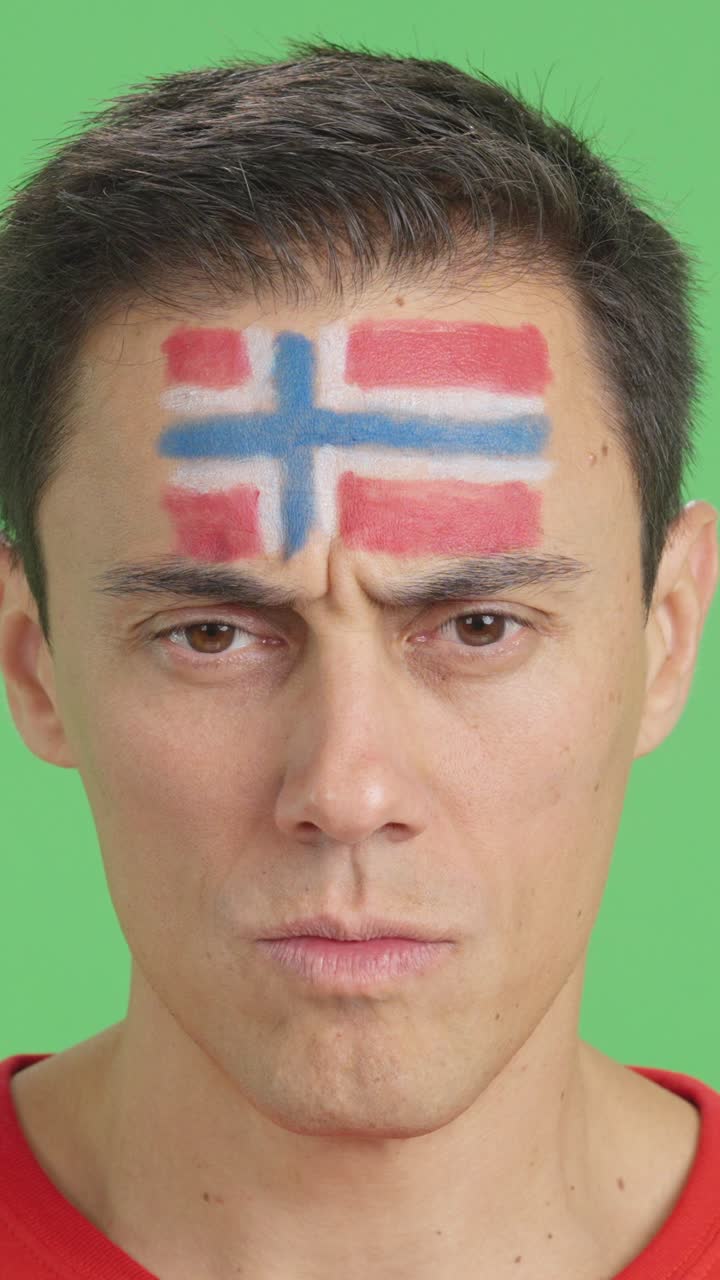 Serious man with a norwegian flag painted on the face