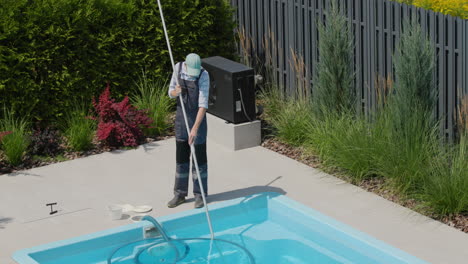 a worker cleans a swimming pool with a special vacuum cleaner. top view