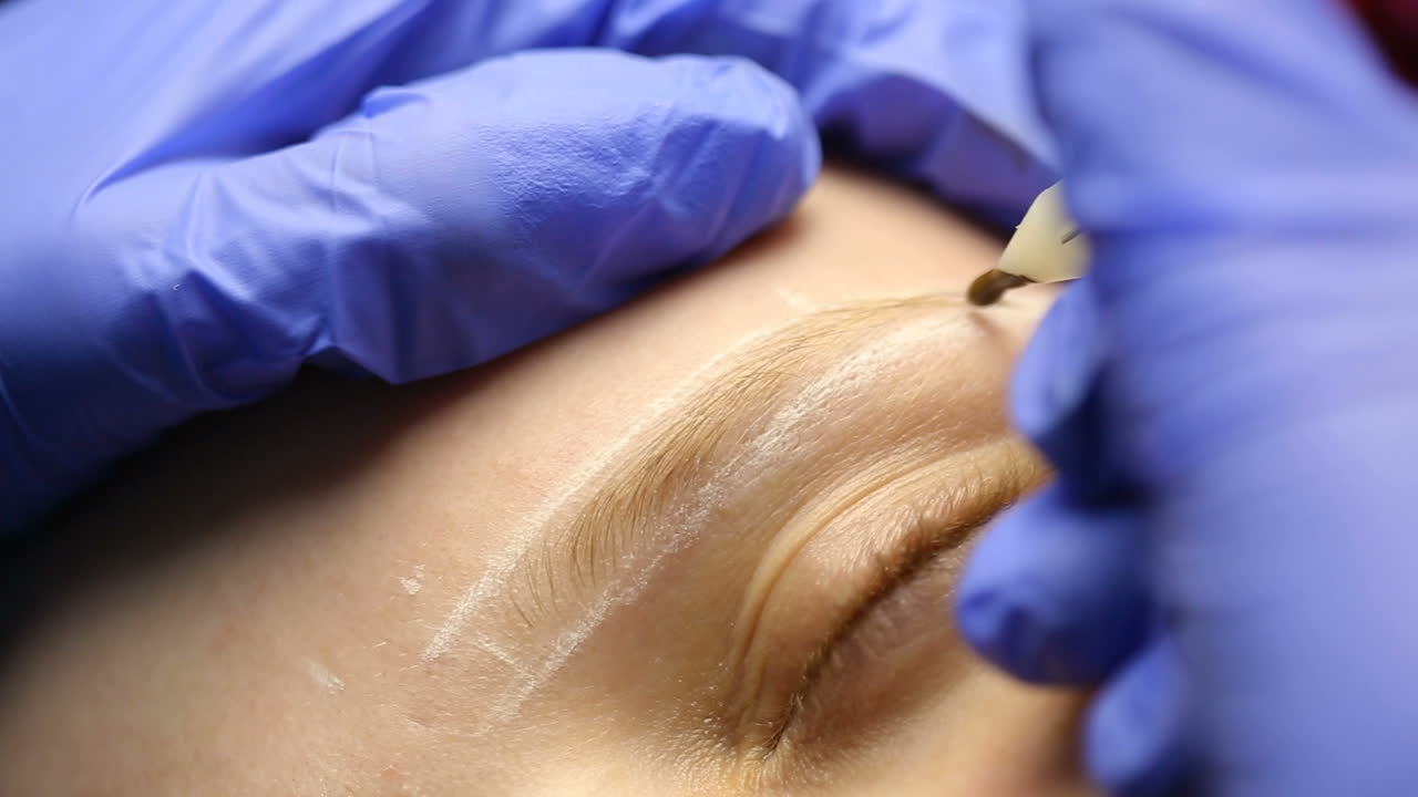 Professional permanent make up. Closeup portrait of lovely young woman getting permanent makeup on her eyebrows
