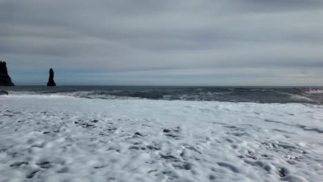 a peaceful sea wave laps at the edge of the sandy beach, creating a beautiful calm atmosphere, black sand beach