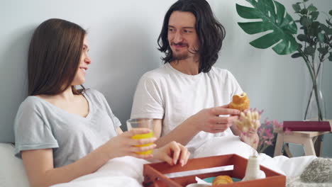 pareja disfrutando del desayuno en la cama