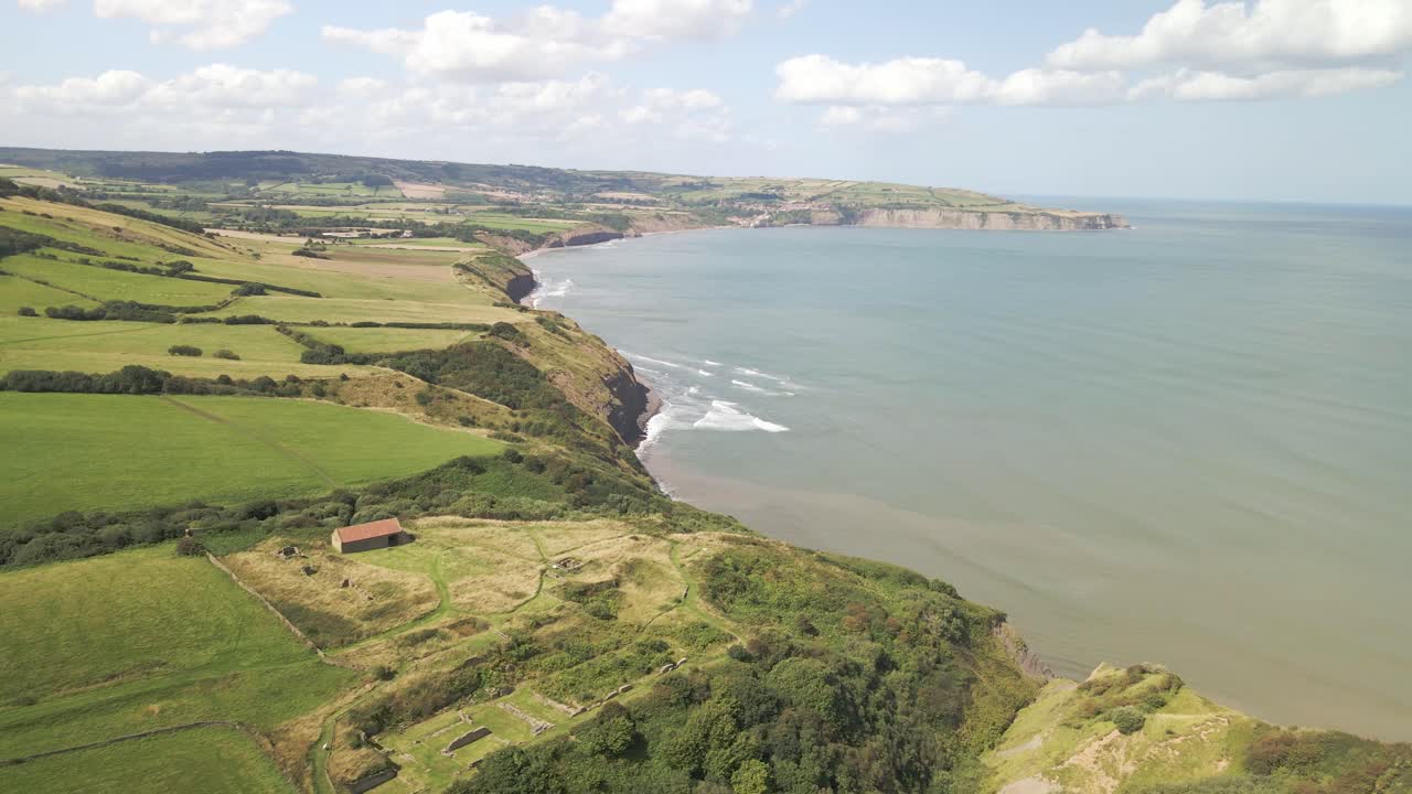 tomada aérea de drones de la costa de north yorkshire cerca de ravenscar con campos verdes y océano