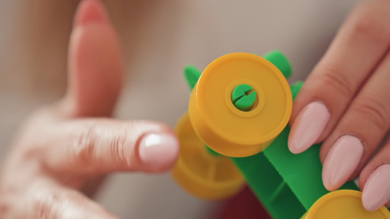 Scena interna: una madre insegna al figlio le abilità motorie. La madre caucasica dimostra un trucco con una ruota giocattolo al chiuso con il bambino, mostrandogli come ruotare la ruota durante un'attività di gioco.