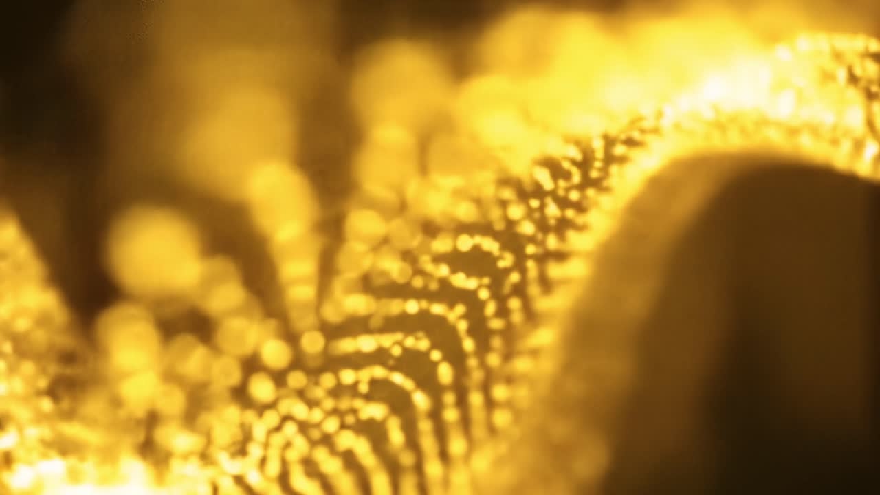 Shimmering golden particles glide and twirl in a dark environment, creating captivating fluid motion and enchanting visual effects that inspire wonder and creativity.