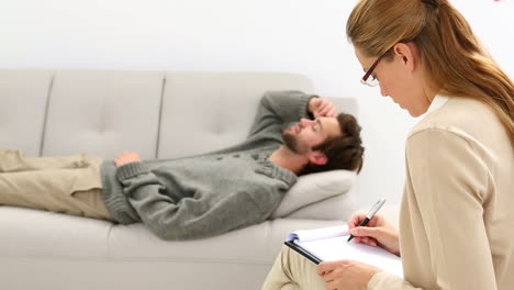 young man lying on sofa talking to his therapist