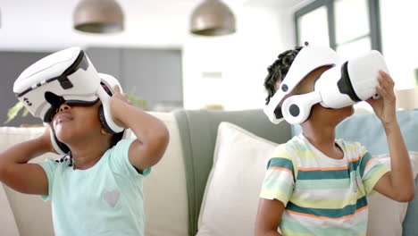 african american sister and brother are engaged with virtual reality headsets at home