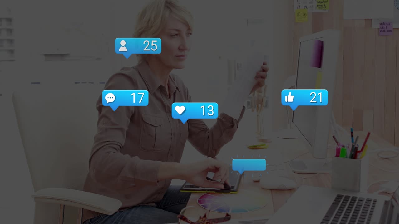 female tech designer grabbing stylus while juggling phone at office desk with floating social icons