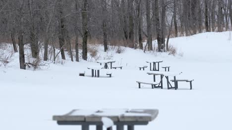 grande plano de mesas de piquenique na praia coberta de neve