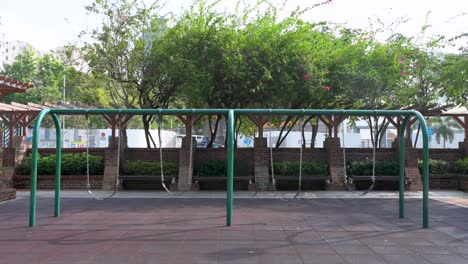 a row of empty swings on a children's playground at a park in hong kong