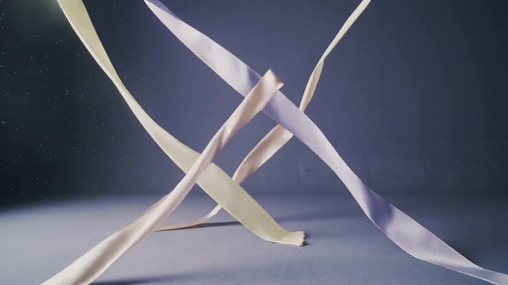 Fan starting, group of satin ribbons twisting and crossing across studio floor, showing dust