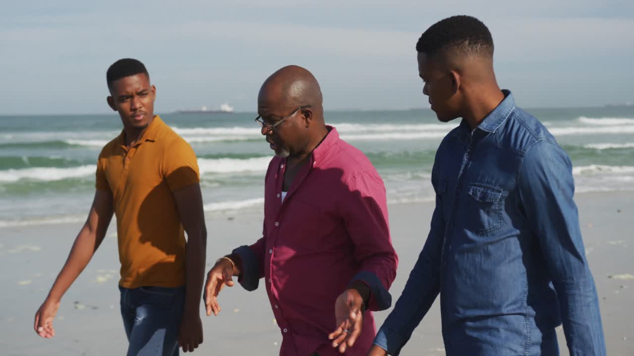 아프리카계 미국인 노인 아버지 와  ⁇ 둥이 십대 아들 들 이 해변 에서  ⁇ 고 이야기 하고 있다