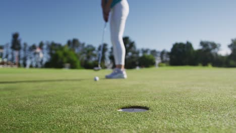 caucasian female golf player taking shot from bunker standing on golf field