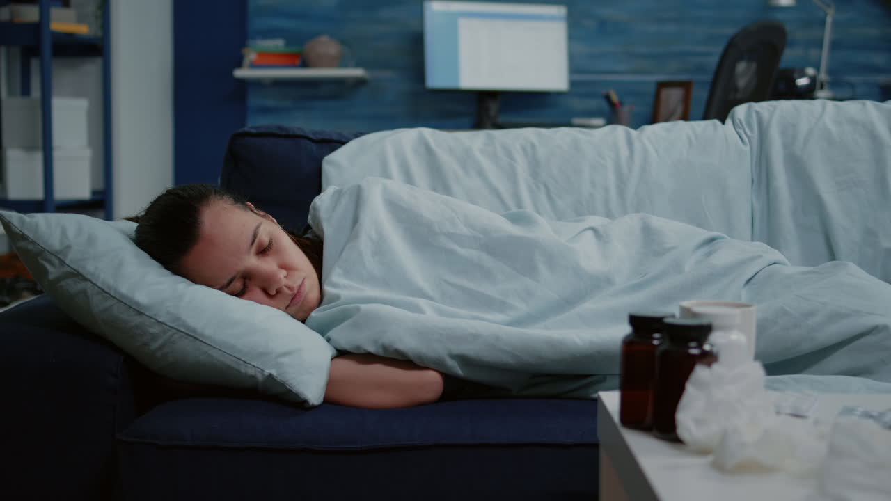 Close up of ill adult laying wrapped in blanket on sofa