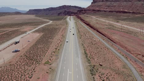 cars traveling through red sandstone valley near moab, utah - aerial