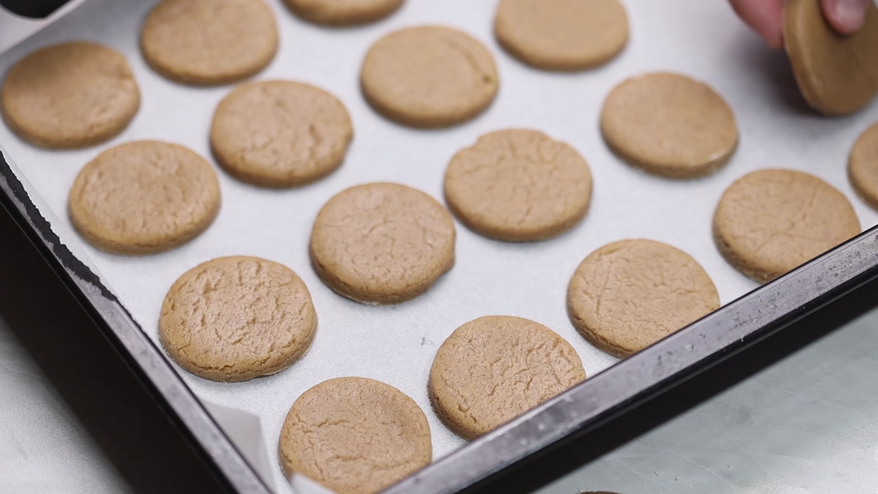 Close up of placing cookie dough pieces on baking tray lined with parchment paper before baking