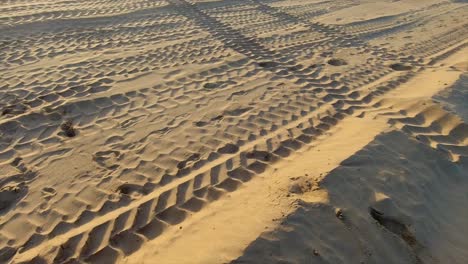 Vista-En-Movimiento-De-Un-Cartel-De-No-Nadar-En-Azul,-Amarillo-Y-Rojo-En-Una-Playa-De-Arena-Desierta-Con-Huellas-De-Neumáticos-En-La-Arena-Sobre-Un-Fondo-Claro