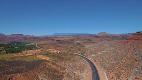 Statische-Drohnenaufnahme-Von-Autos,-Die-Eine-Kurvenreiche-Straße-In-Der-Nähe-Von-Mount-Zion-Hinunterfahren,-Mit-Einer-Bergkette-Im-Hintergrund-Im-Süden-Von-Utah