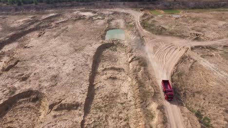 vista aérea de un camión de basurero rojo en una cantera de arena