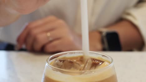 hand stirring iced coffee with a straw