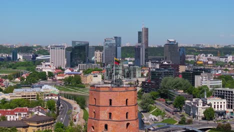 amazing drone shot above gediminas tower, lithuanian flag toward vilnius business district