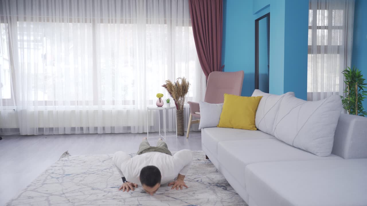 건강한 몸매를 가진 젊은이가 집에서 근육을 키우기 위해 버피를 하고 있습니다.