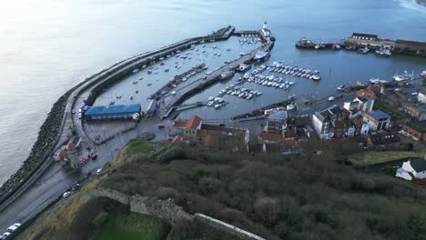 aerial parallax shot of a curved road above a river with few boats beside a city of scarborough, north yorkshire in england during summer