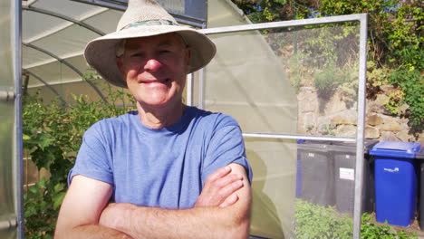 portrait of senior male gardener outside allotment greenhouse