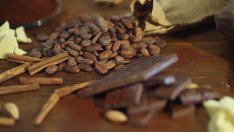 mano femenina poniendo granos de cacao con barras de chocolate en la mesa