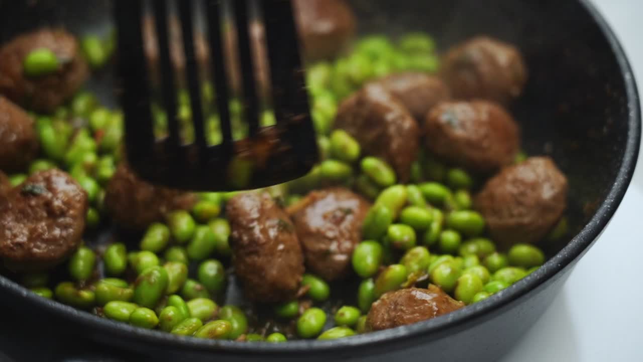 Unrecognizable person cooking green beans and meatballs