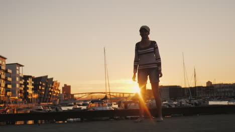 active woman rejoices at sunrise over the marina runs forward raises his hands up sunrise in bergen