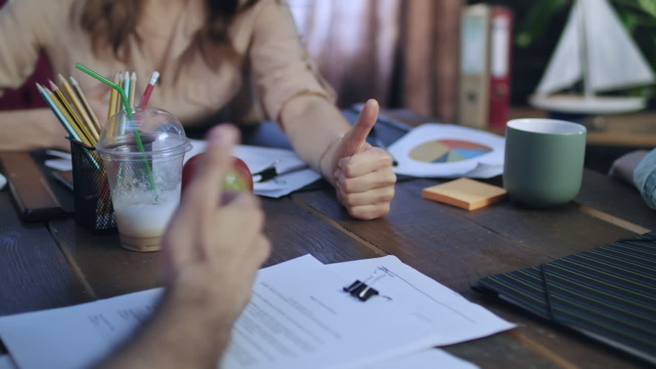 Woman boss showing thumbs up on table at business meeting