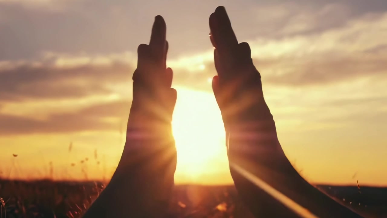 Silhouette di mani che si danno il cinque contro un tramonto dorato