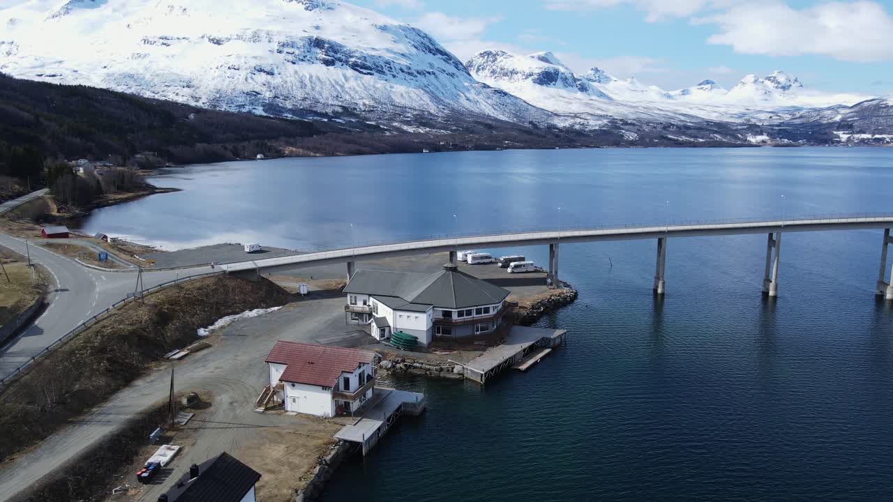 panorámica aérea del hotel turístico del centro ártico junto a las tranquilas aguas del fiordo de gratangen y las impresionantes montañas nevadas