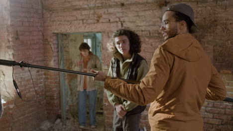 man production worker holding a microphone on a movie recording in a ruined building