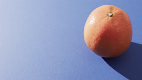 Video-of-close-up-of-orange-with-copy-space-over-blue-background