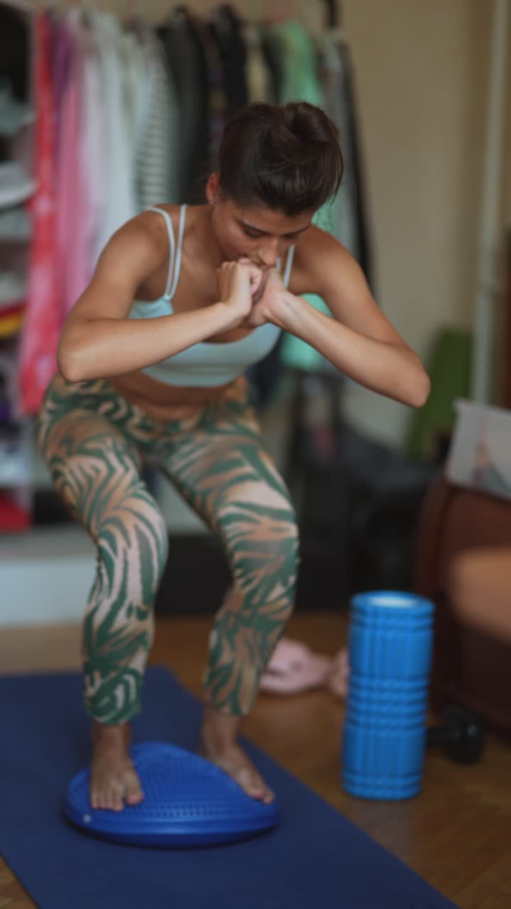 mujer haciendo ejercicio de yoga en cuclillas en una tabla de equilibrio