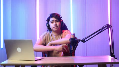 asian man playing video game with mobile phone then smiles to camera while live stream