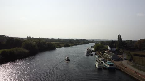 drone video moves sideways across the river trent in the nottinghamshire countryside as a river boat sails along the river pass some moored boats on the right