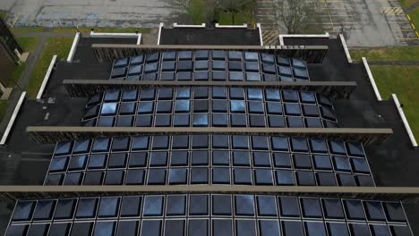 an aerial view over a building with many unique, square skylights on the roof on a cloudy day on long island, new york