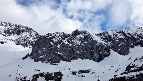 cámara de lapso de tiempo de izquierda a derecha panorámica de montañas nevadas con cielo azul y nubes rodando sobre las cimas de las montañas