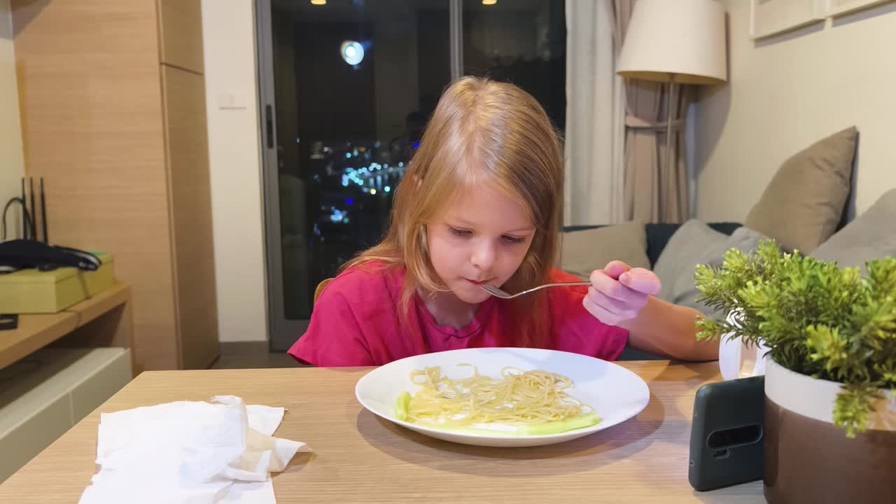 Un bambino mangia noodles al tavolo