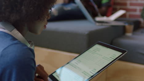 young-black-business-woman-using-tablet-browsing-corporate-project-documents-on-portable-computer-technology-colleagues-working-together-in-brainstorming-in-office