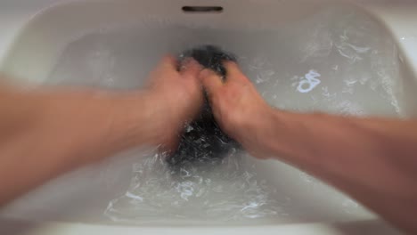 hombre lavándose las manos en la camisa en el lavabo del baño