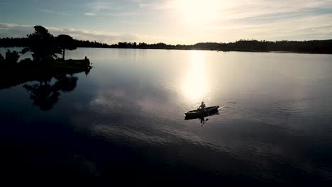 beautiful colorado sunrise on a lake with a silhouette of a canoe against the rising sun