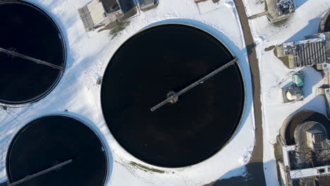 top-down-aerial-of-basin-at-sewage-water-treatment-plant-in-winter---drone-lifting-up